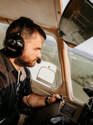 A male pilot with headset navigates a small aircraft in flight, capturing a focused cockpit environment.