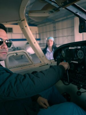 Confident pilot seated in an airplane cockpit, preparing for takeoff inside a hangar.