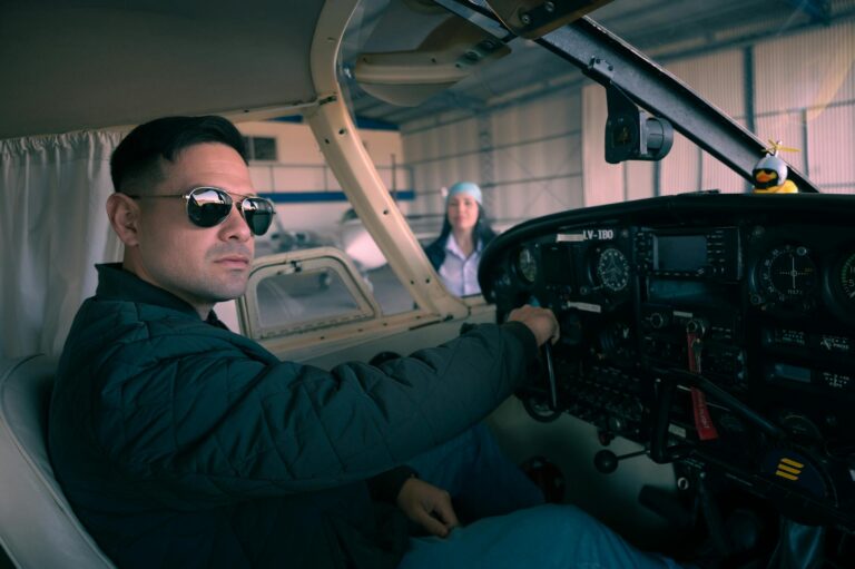 Confident pilot seated in an airplane cockpit, preparing for takeoff inside a hangar.